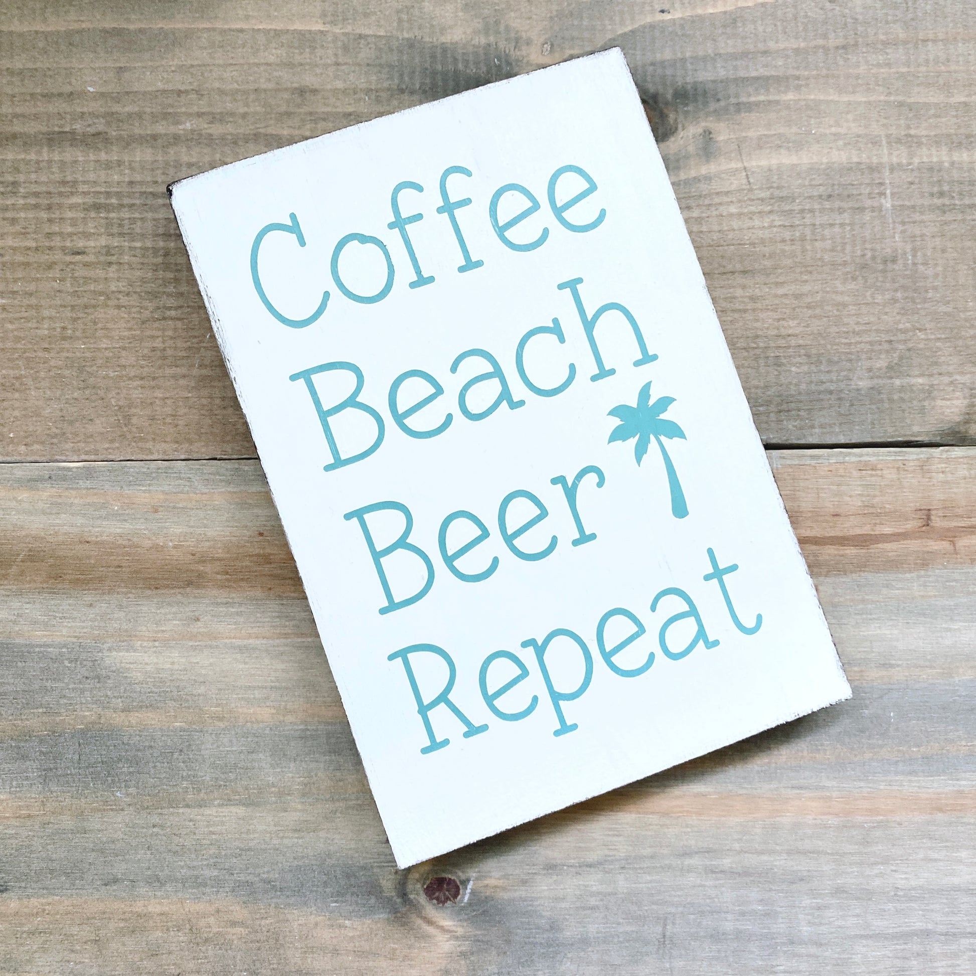 coastal wood signwith 'Coffee Beach Beer Repeat' text on a wooden surface
