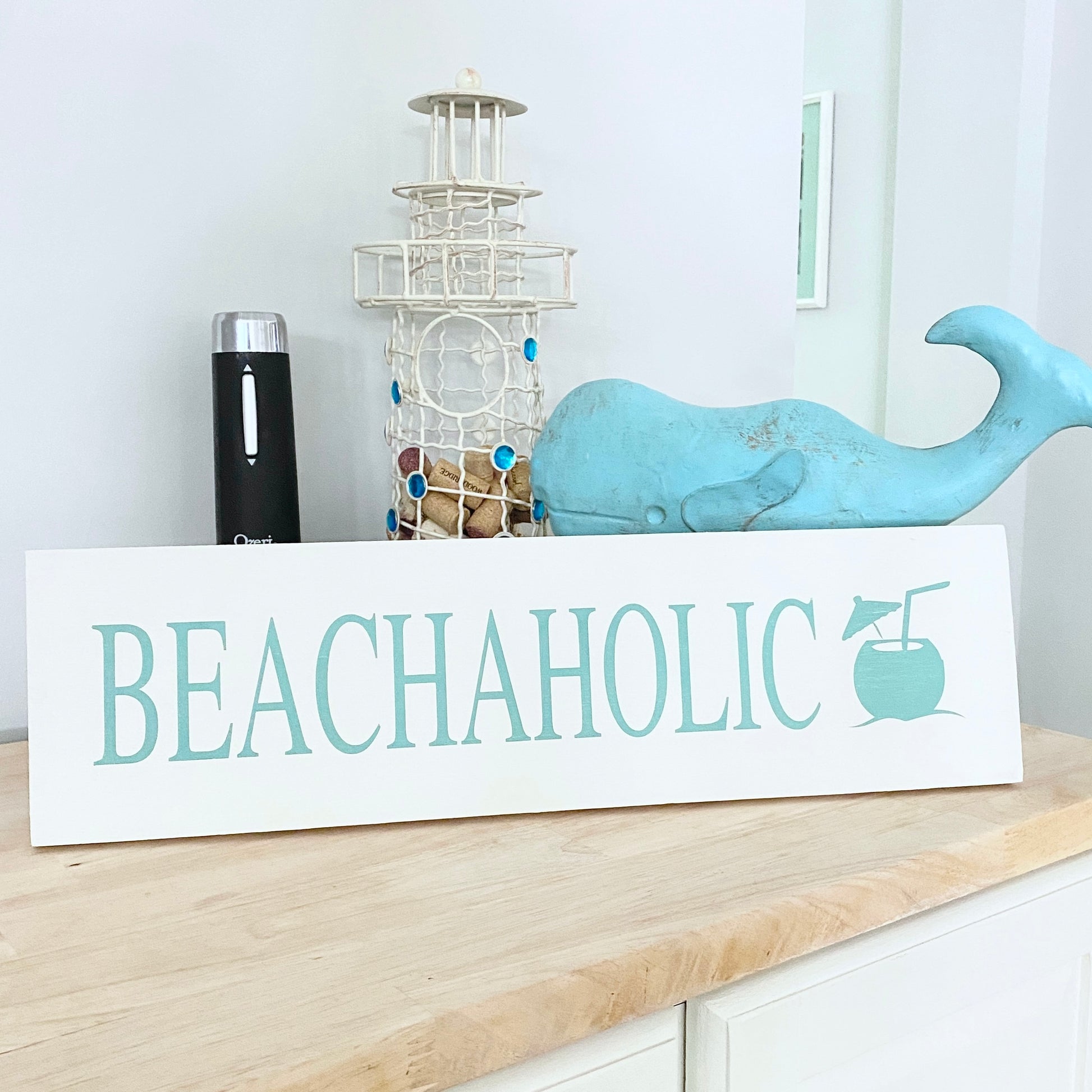 Decorative sign with 'BEACHAHOLIC' text on a shelf with decorative items.