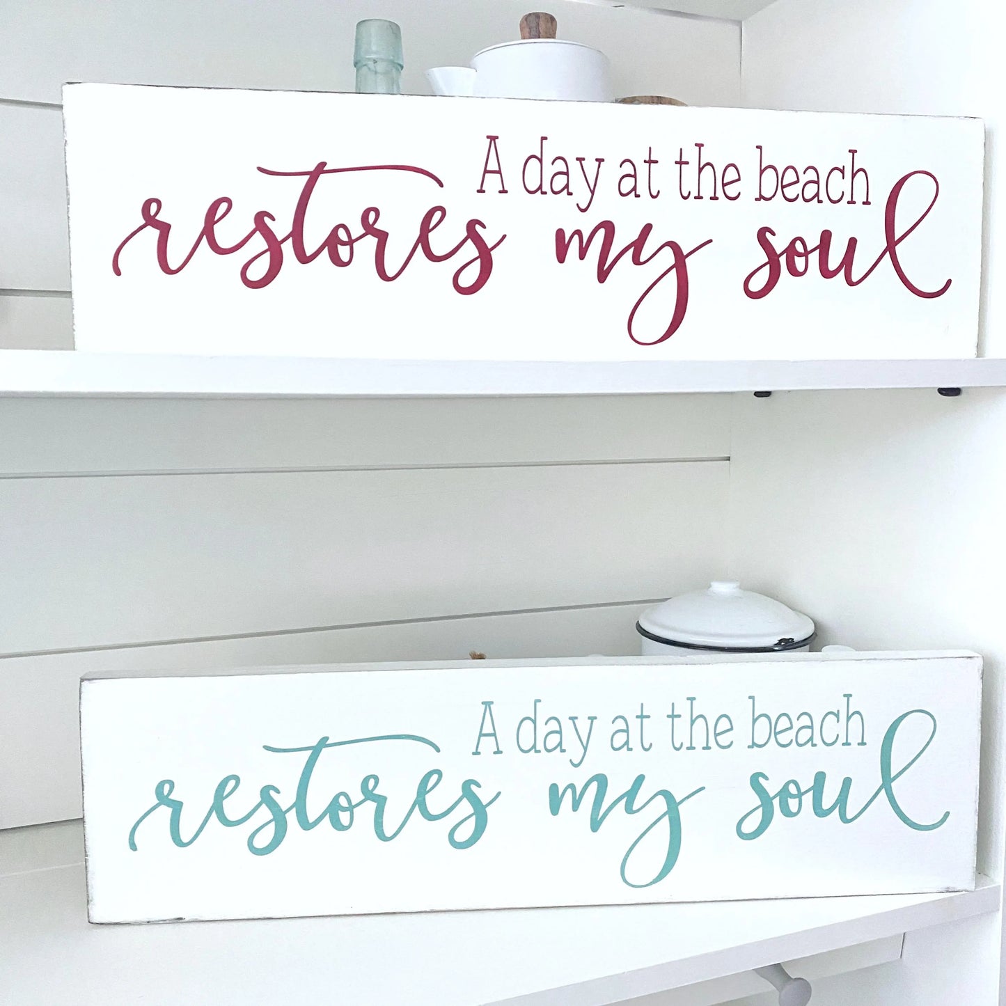 Wooden signs with 'A day at the beach restores my soul' text on a white shelf.