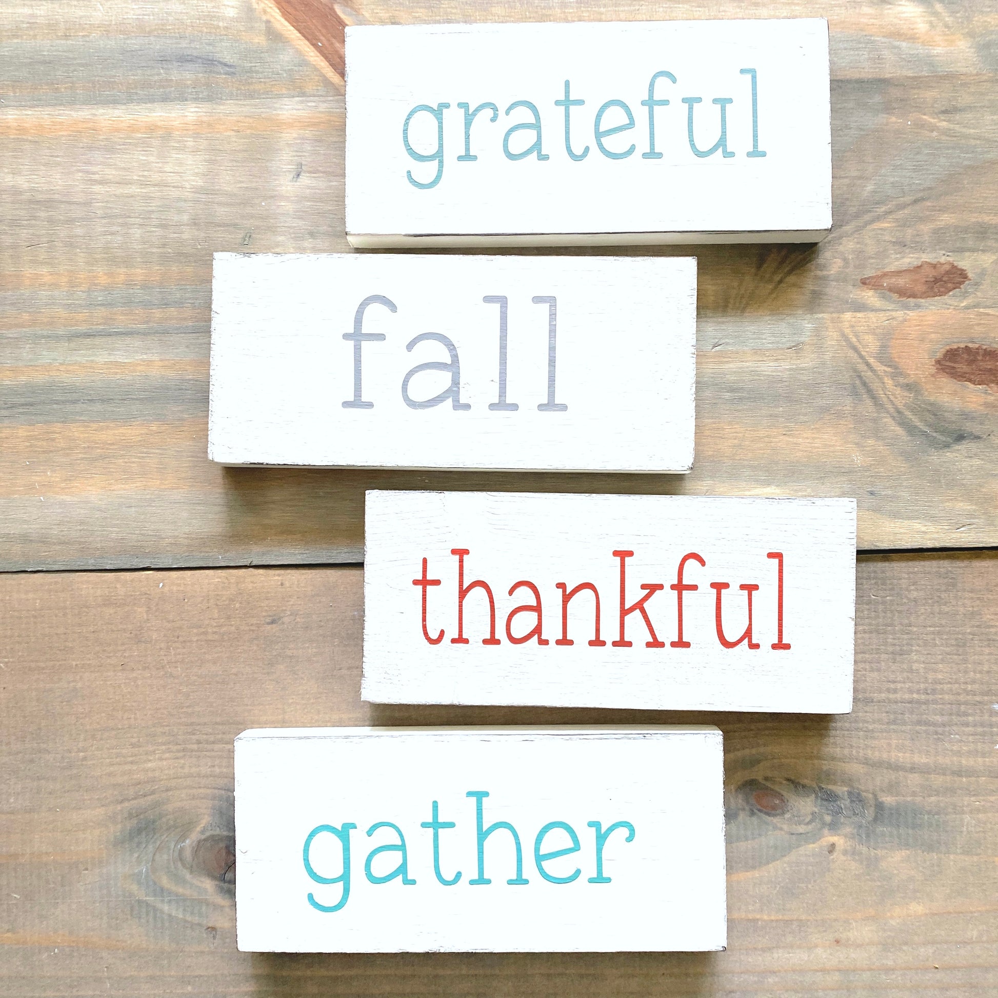 Set of wooden blocks with words 'grateful', 'fall', 'thankful', and 'gather' on a wooden surface.