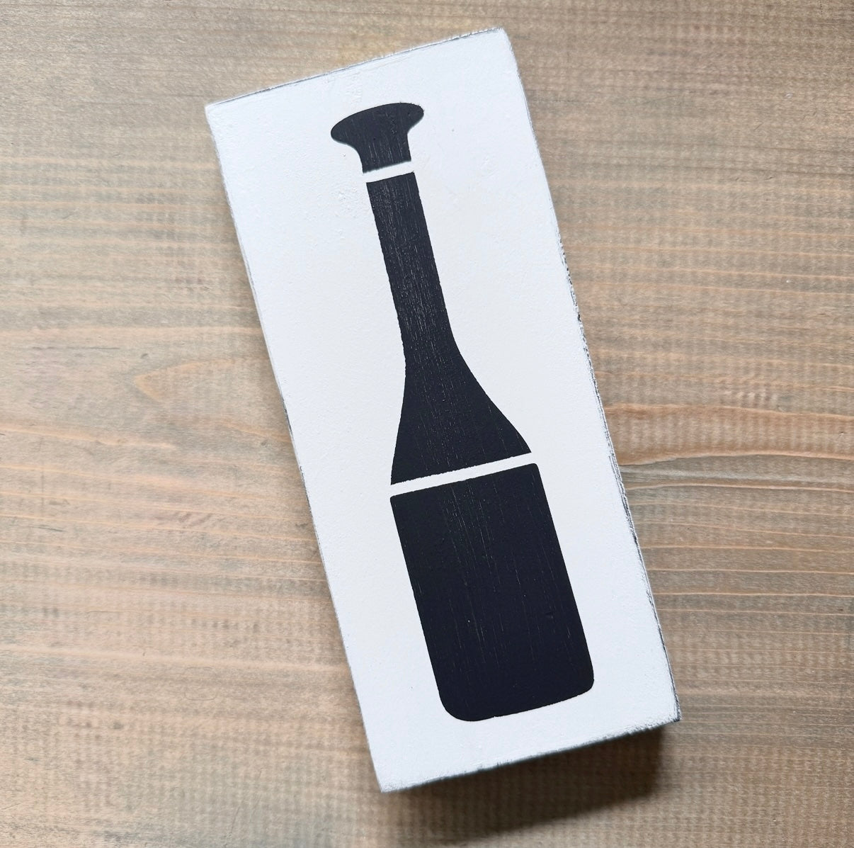 White sign with a black oar design on a wooden surface