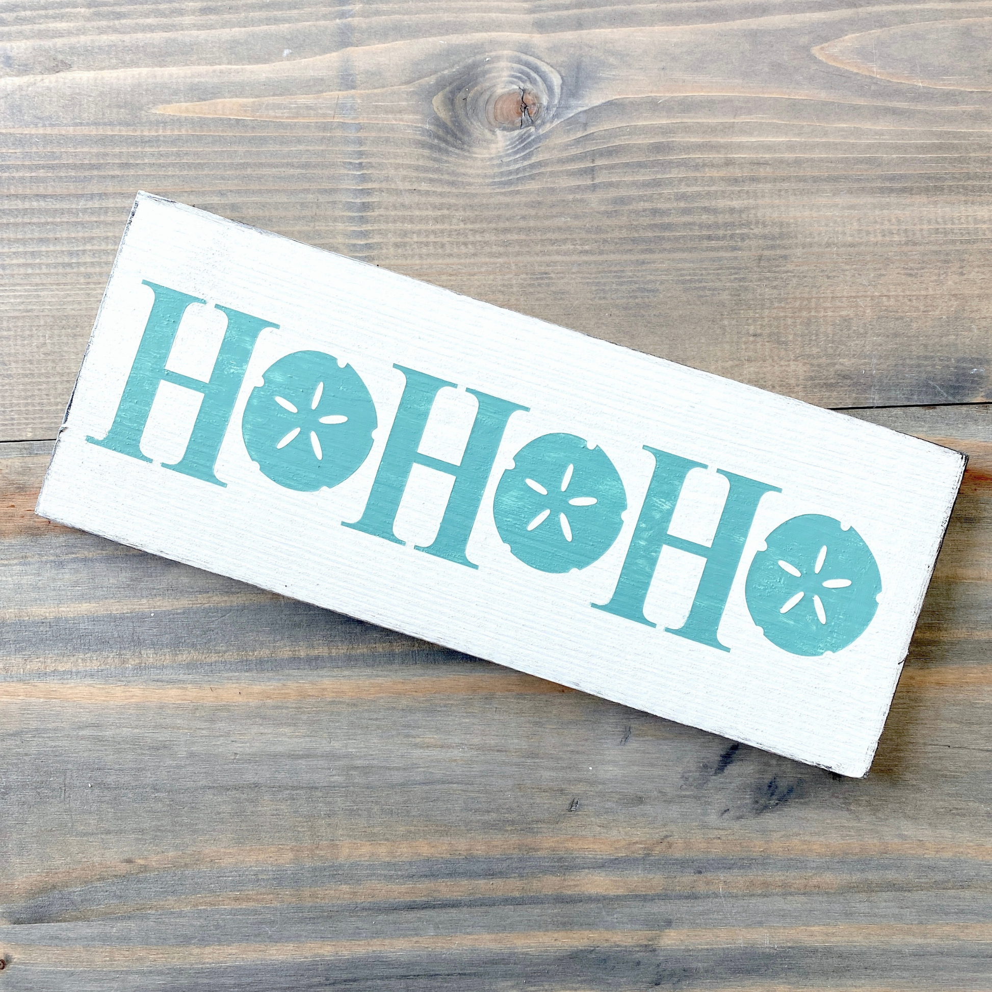 Wooden sign with 'HO HO HO' text on a wooden surface