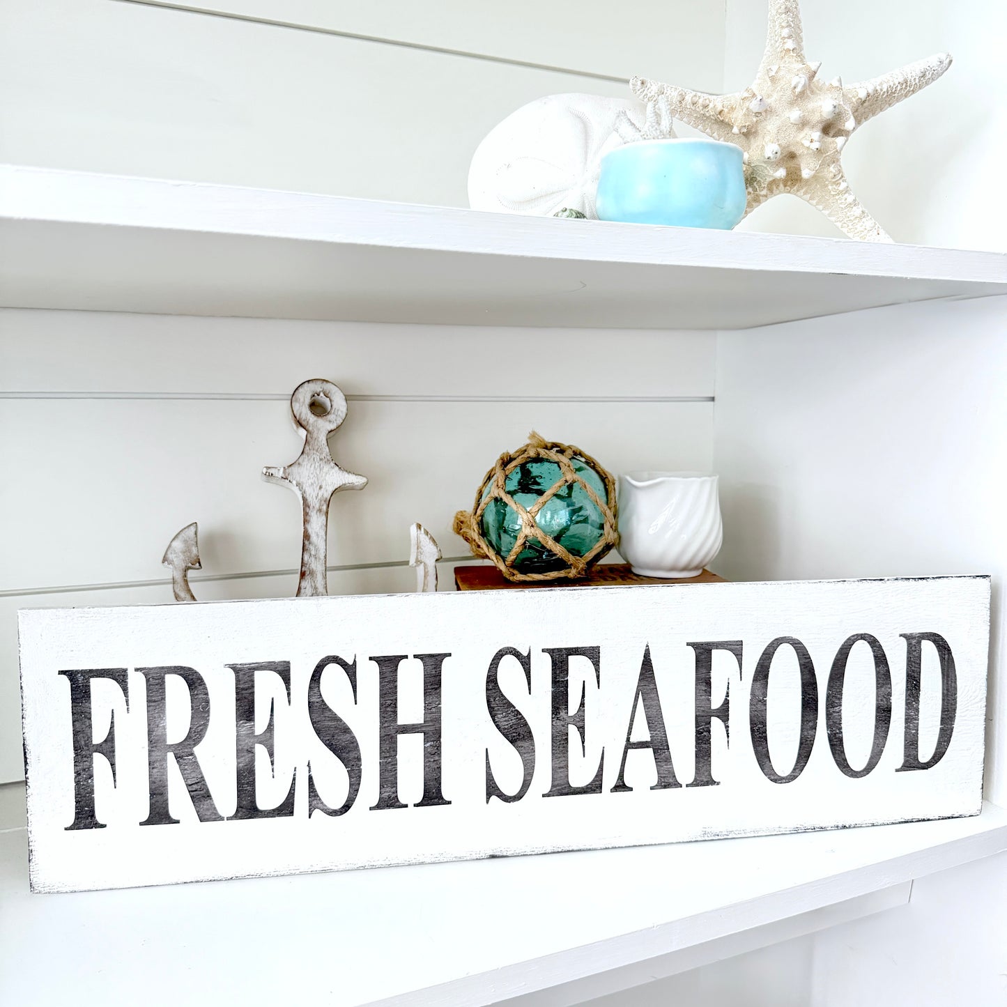 Fresh Seafood sign on a decorative shelf with coastal decor