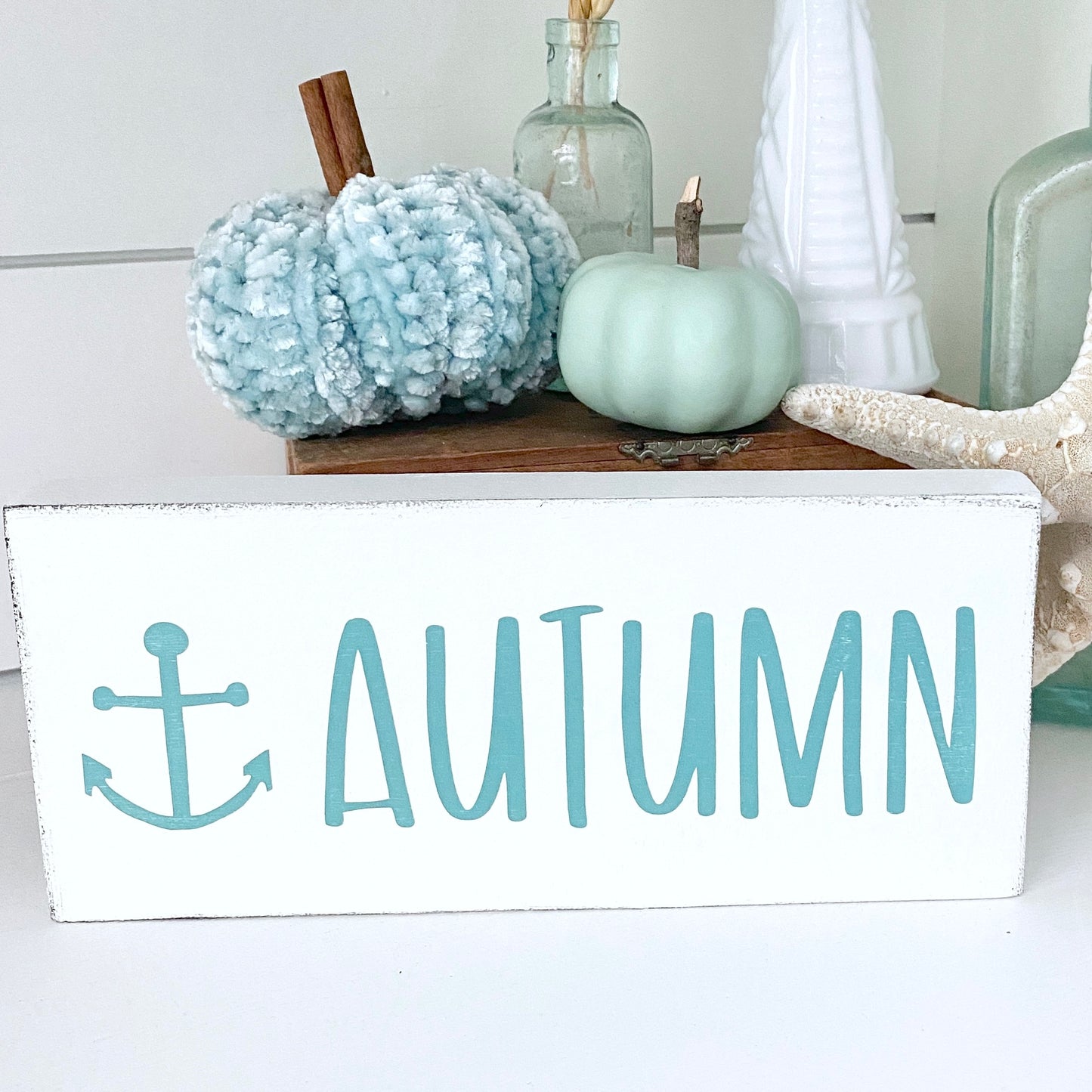 Decorative sign with 'Autumn' text anchor and pumpkins on a shelf.