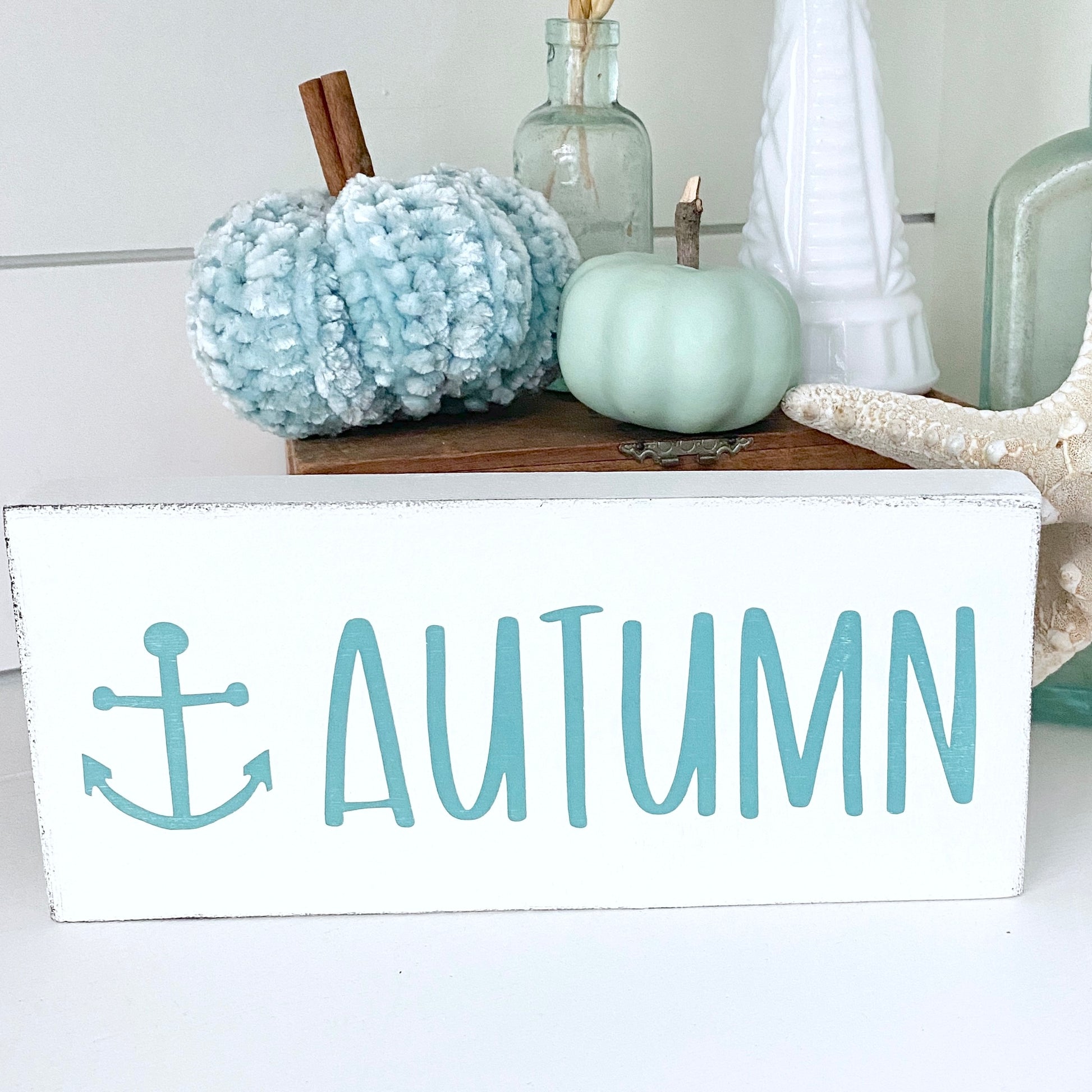 Decorative sign with 'Autumn' text anchor and pumpkins on a shelf.