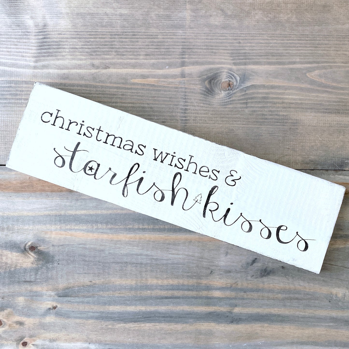 Wooden sign with 'christmas wishes & starfish kisses' text on a wooden surface