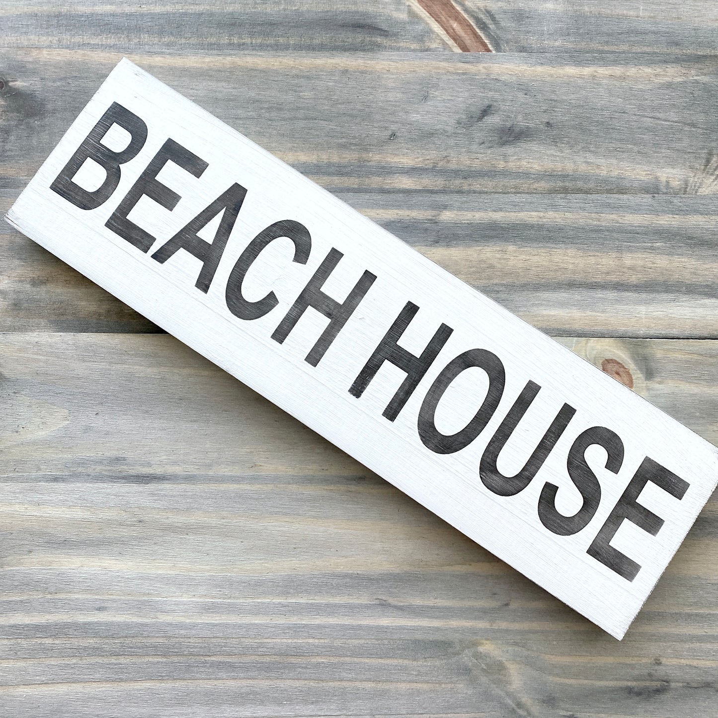 Wooden sign with 'BEACH HOUSE' text on a wooden background