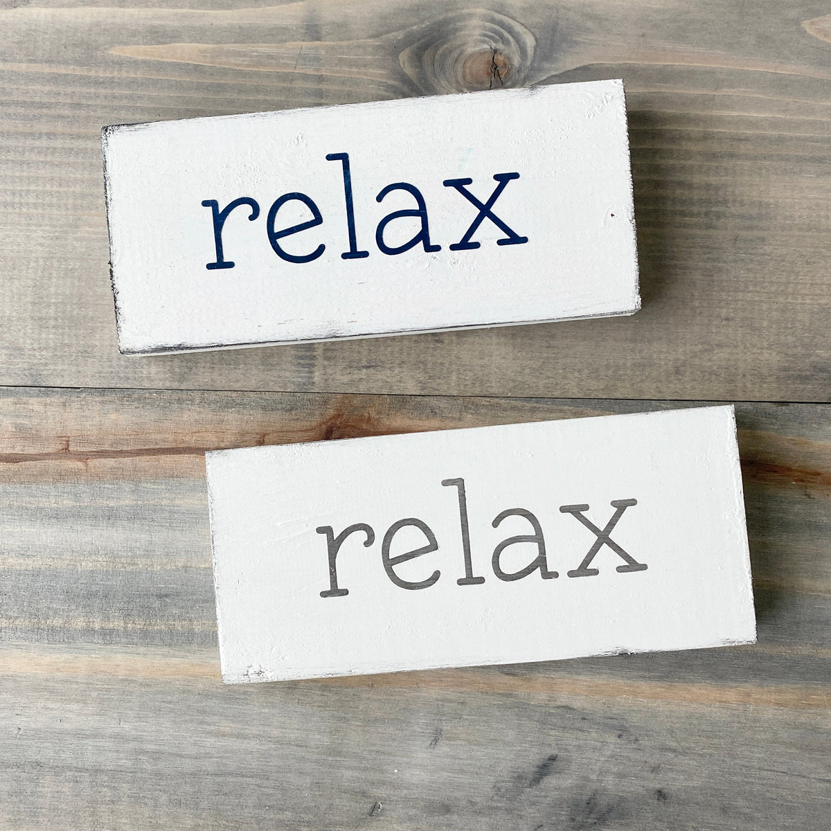 Two wooden signs with 'relax' text on a wooden surface