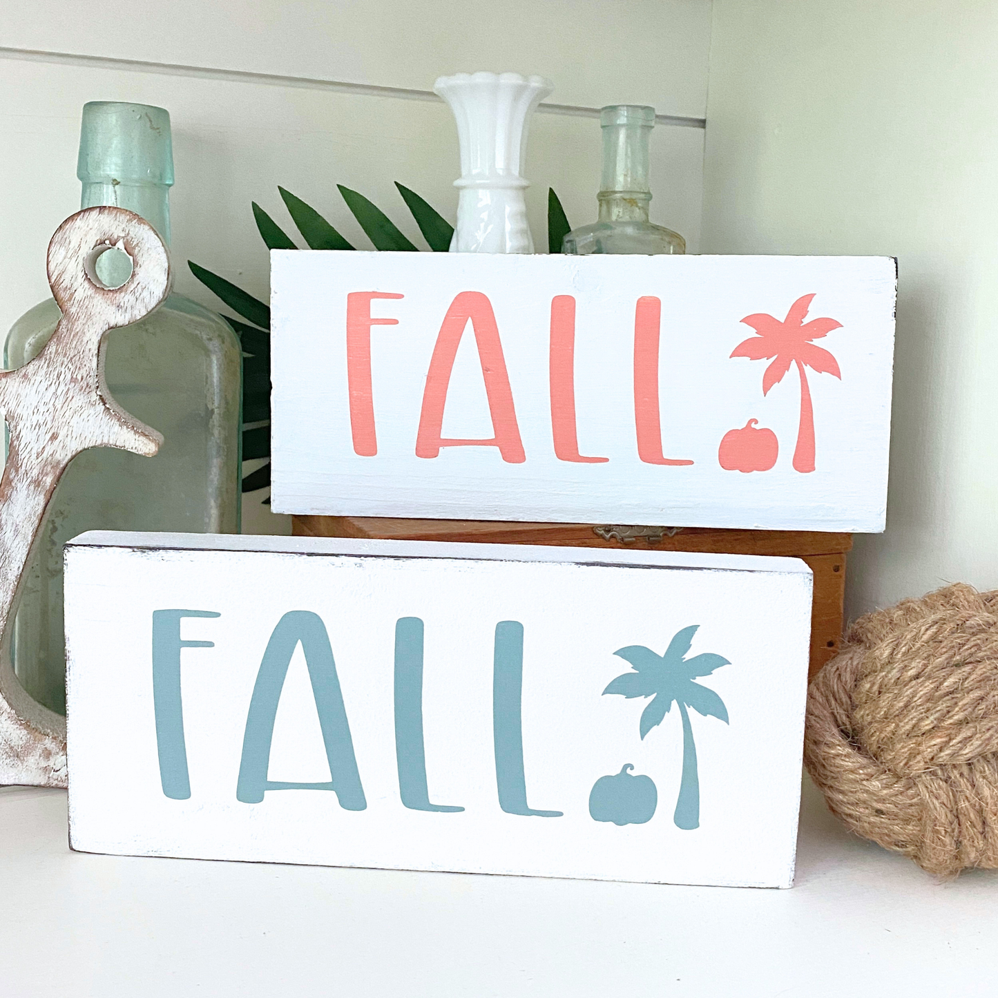 Two 'FALL' signs with decorative elements on a shelf.