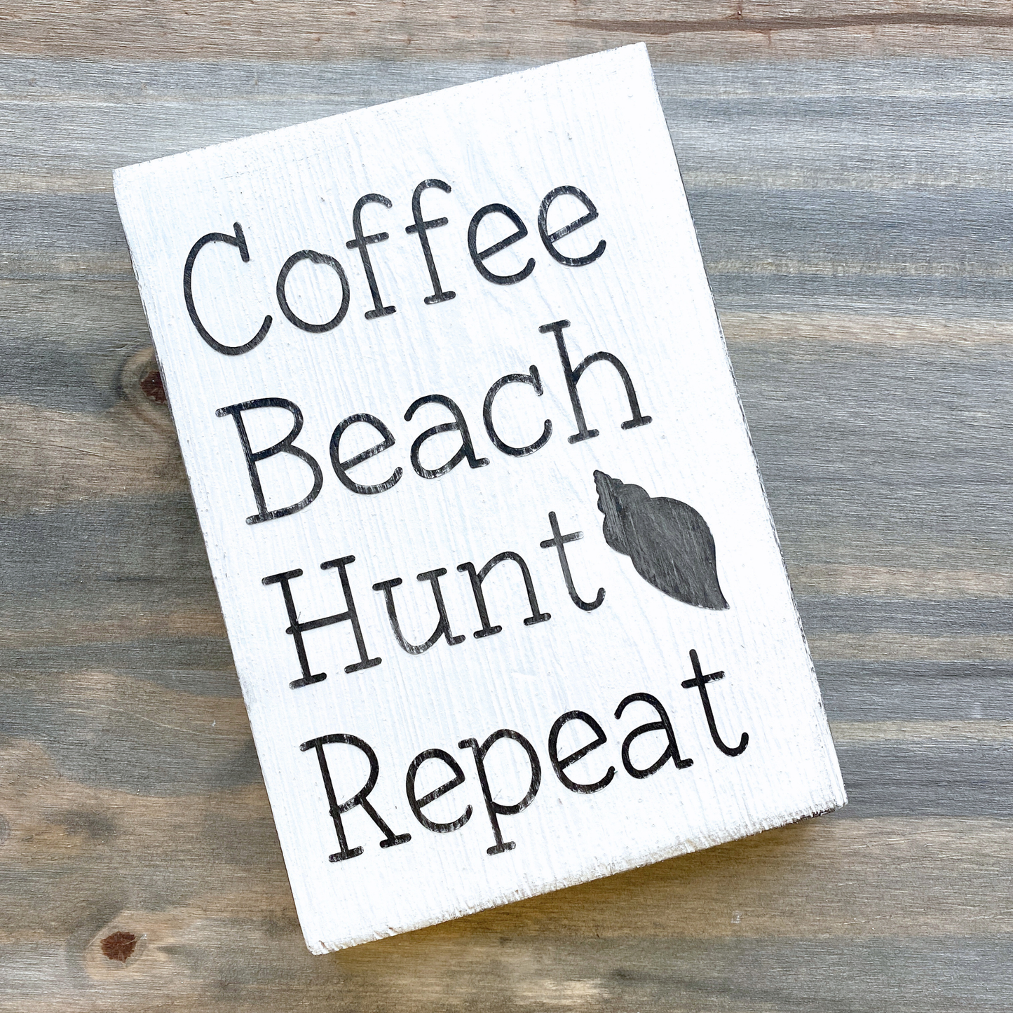 Wooden sign with 'Coffee Beach Hunt Repeat' text on a wooden surface