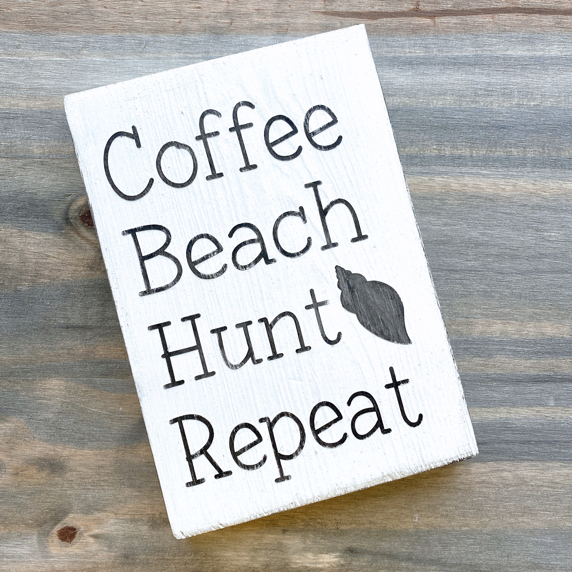 Wooden sign with 'Coffee Beach Hunt Repeat' text on a wooden surface