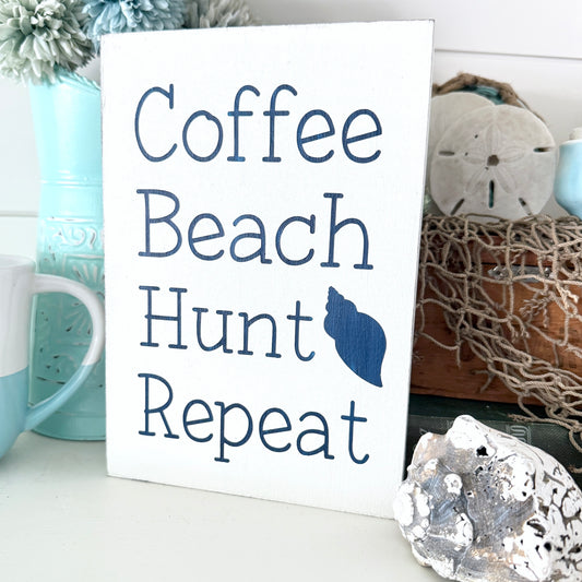 Sign with 'Coffee Beach Hunt Repeat' text on a decorative background with mugs and shells.