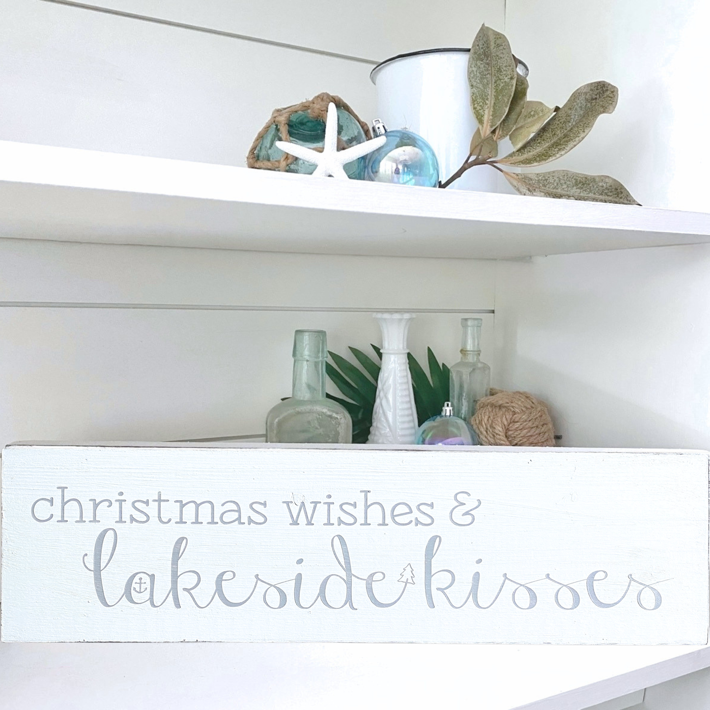 Decorative shelf with Christmas-themed decor and a sign reading 'Christmas wishes & lakeside kisses'.