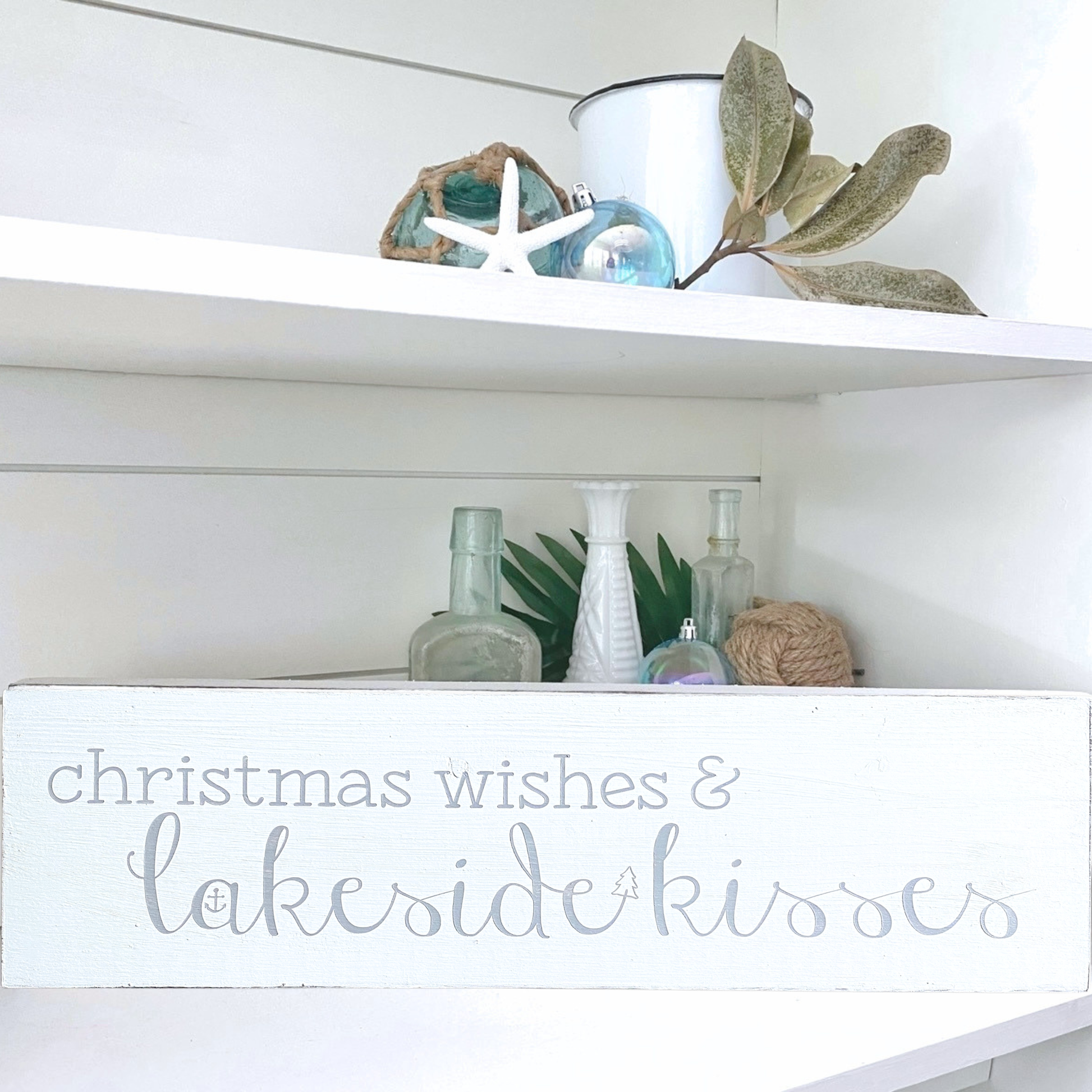 Decorative shelf with Christmas-themed decor and a sign reading 'Christmas wishes & lakeside kisses'.